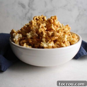 White bowl filled with cracker jack style crunchy caramel corn with lots of peanuts, ready to be enjoyed.