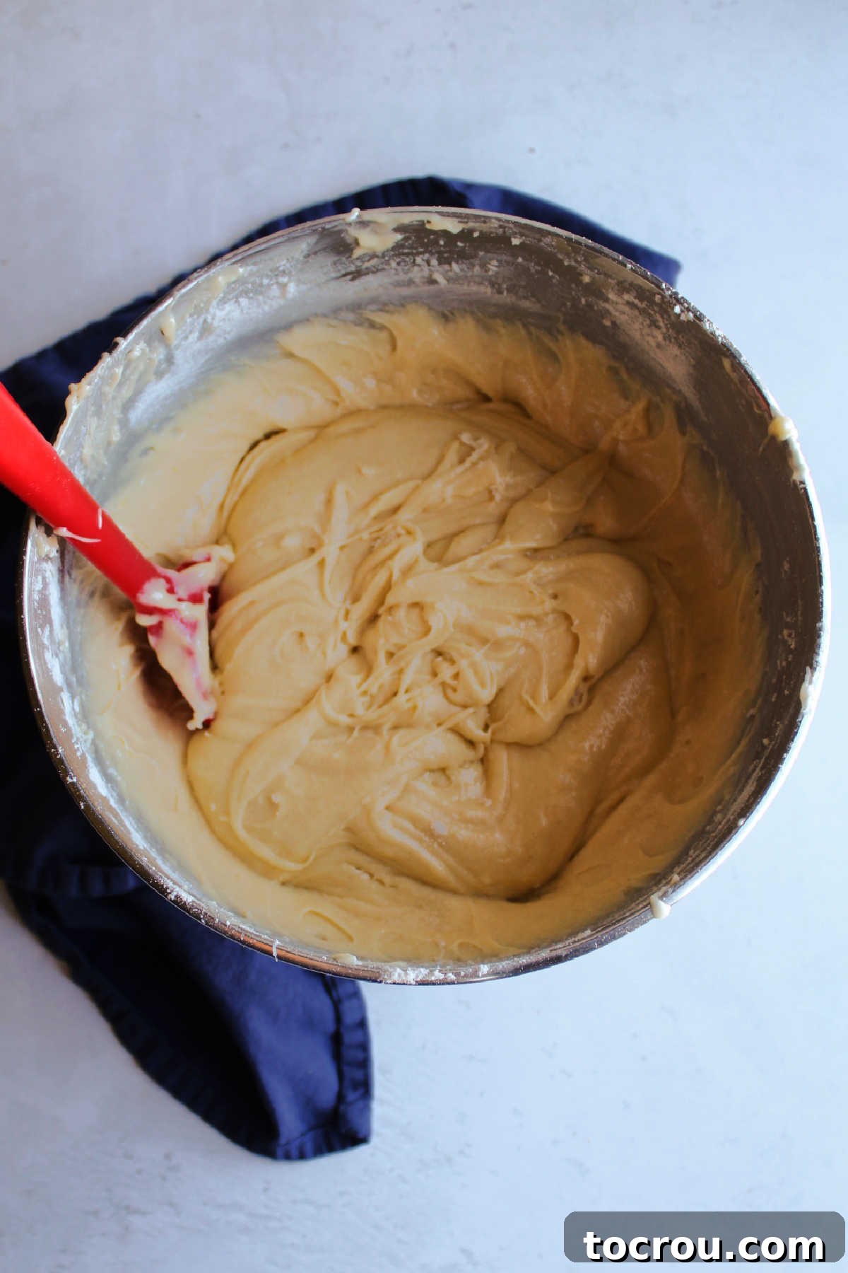 Mixer bowl filled with vanilla cake batter ready to be poured into sheet pan and baked. 