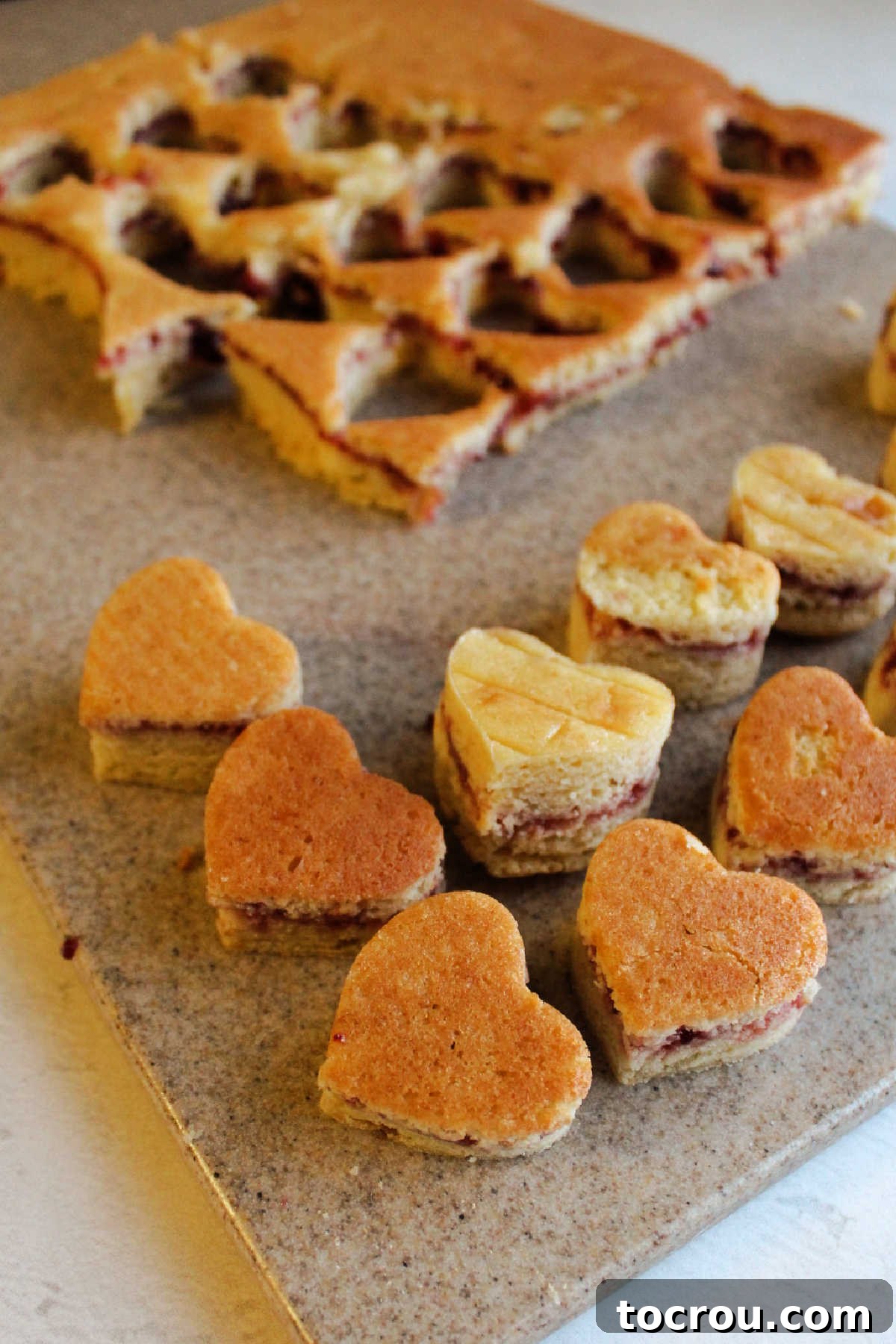 Cutting heart shapes out of raspberry filled petit four cake.