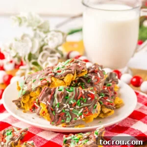 A festive plate of cornflake brittle, featuring a rich chocolate layer topped with vibrant red and green candy melt swirls and sprinkles, perfect for Christmas.