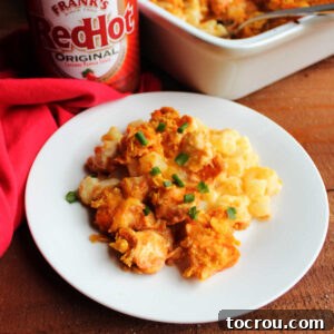 A hearty plate of buffalo chicken casserole, featuring cheesy ranch potatoes topped with spicy chicken and a golden cornflake crust, ready to be enjoyed.