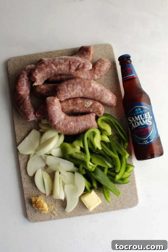 Ingredients laid out on a cutting board: raw bratwursts, sliced onions, sliced green bell peppers, minced garlic, butter, and a bottle of beer.