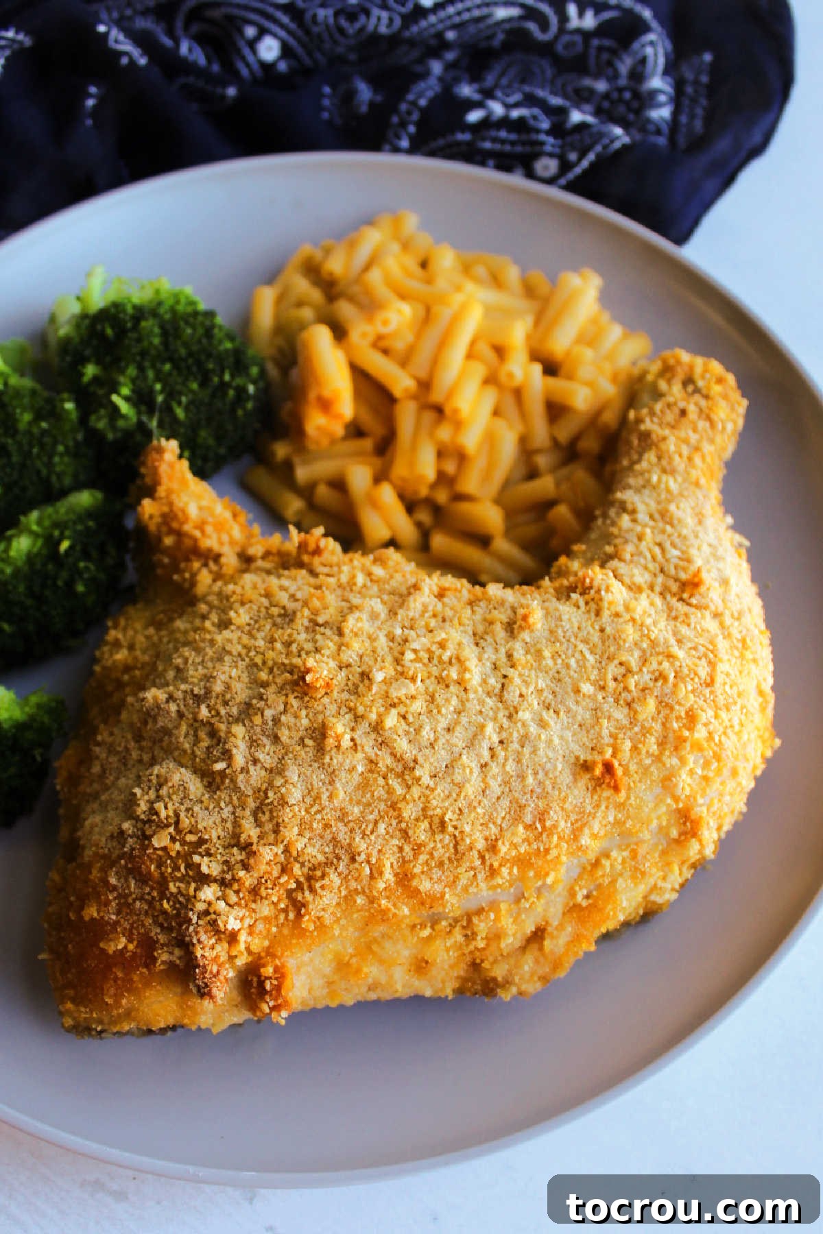 Close up of chicken leg quarter coated in cornflake crumbs and seasoned salt ready to eat. 