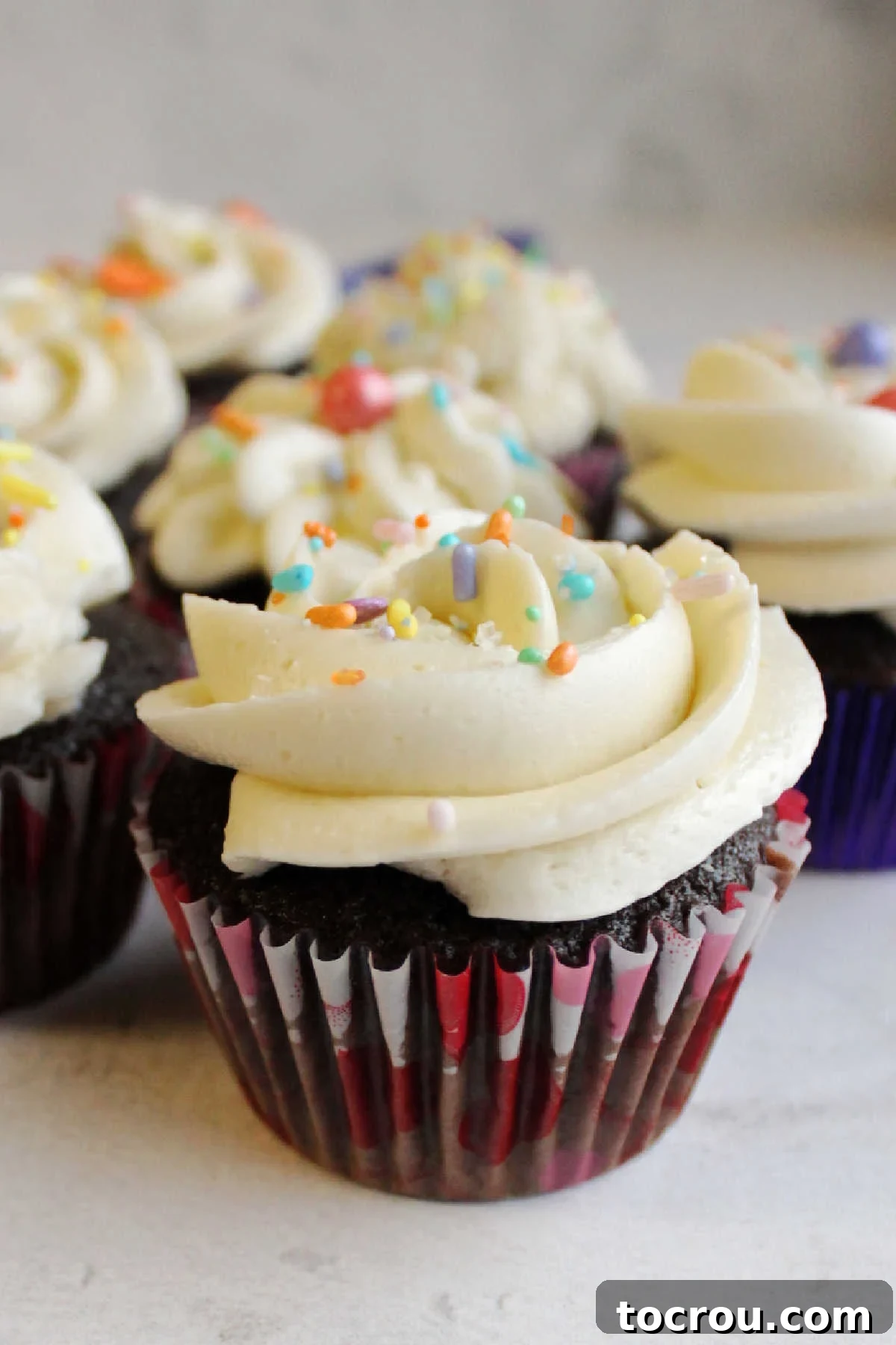 Looking across chocolate cupcake topped with swirls of white swiss meringue buttercream. 