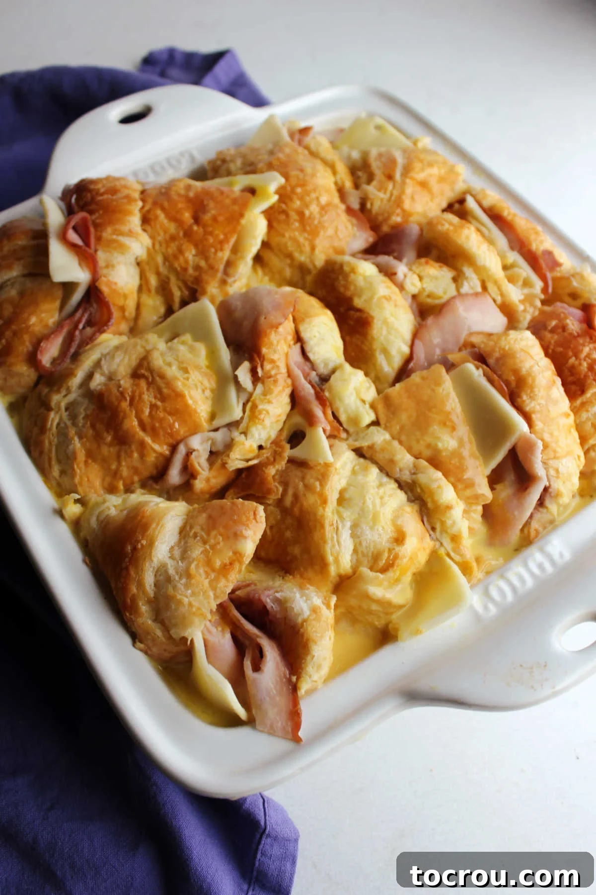 Sandwiches thoroughly soaked in creamy egg custard inside the baking pan, covered and ready for chilling before their perfect bake.