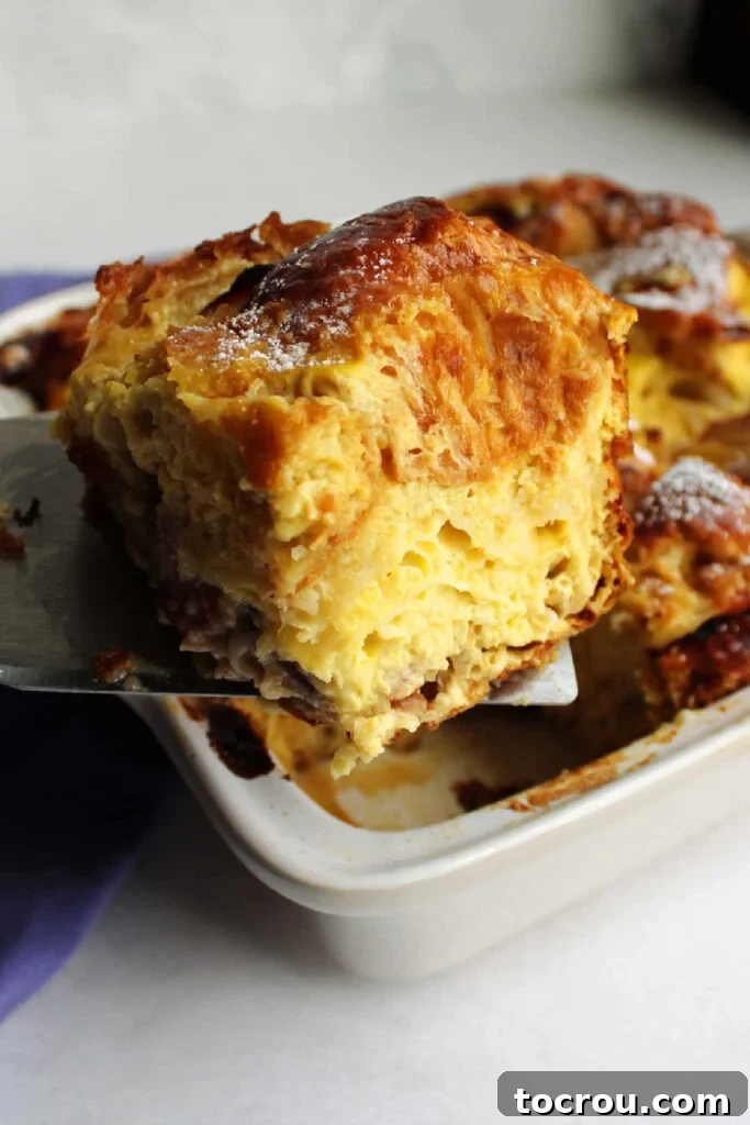 A serving spatula carefully lifting a perfect, golden-brown slice of Monte Cristo casserole from the baking pan.