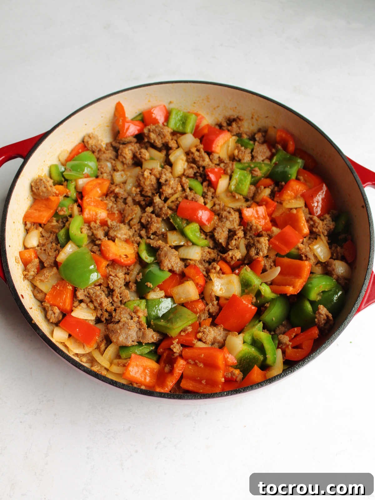 Sautéed Chorizo and Veggies A large cast iron pan brimming with sautéed green bell pepper, red bell pepper, onion, and browned chorizo, creating a fragrant and colorful base for the creamy pasta.