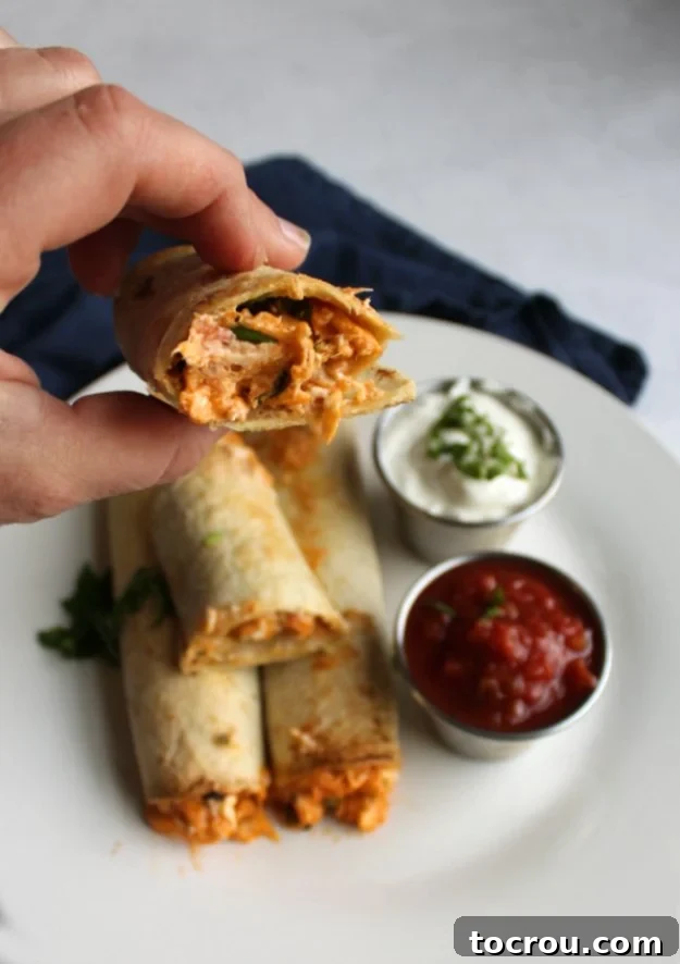 Perfectly Baked Taquito Hand holding a crispy, golden-brown creamy chicken taquito, highlighting the shredded chicken filling.