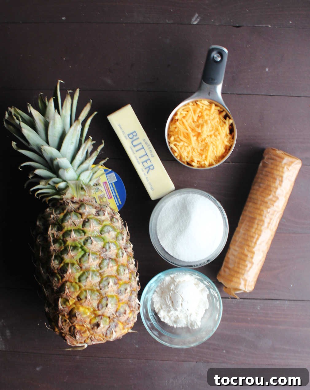 Crackers, butter, cheese, flour, sugar and a fresh pineapple ready to be made into southern casserole.