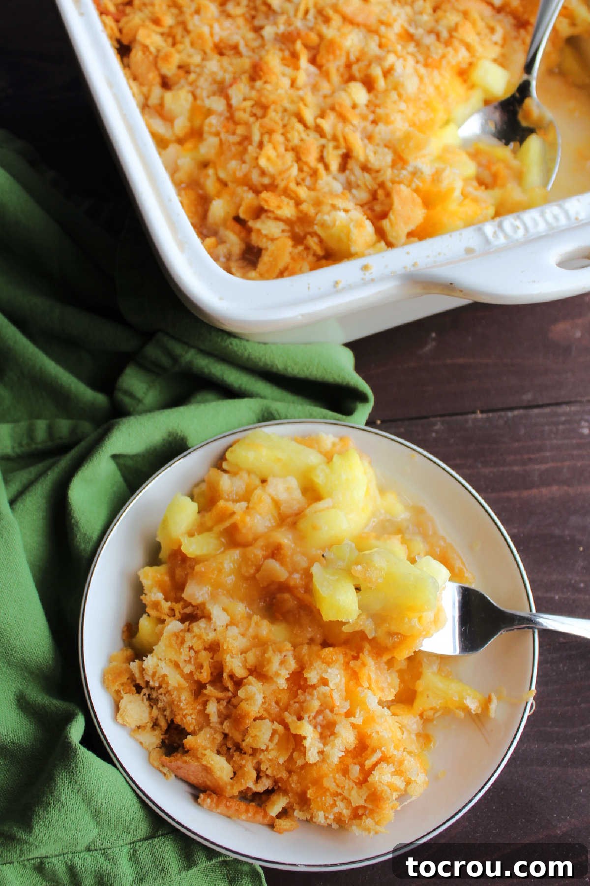 Looking down on pineapple casserole showing gooey pineapple topped with golden cracker crumbs and melted cheddar cheese. 
