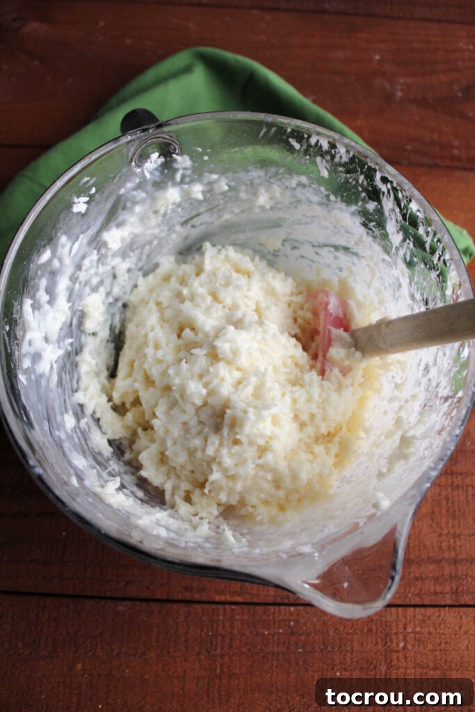 A large mixing bowl containing the creamy, sweet coconut mixture with sweetened condensed milk and powdered sugar, ready for shaping.