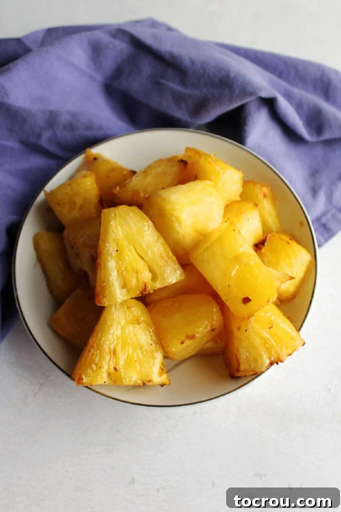 Bowl of glossy butter and brown sugar coated pineapple that has been cooked in an air fryer.