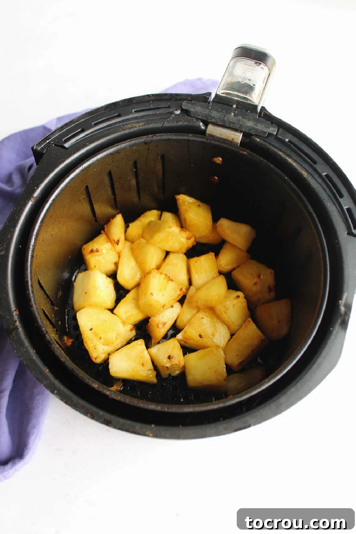 Pineapple chunks in air fryer basket, ready to go.