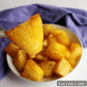 Chunk of air fried pineapple coated in butter and brown sugar on fork, ready to eat.