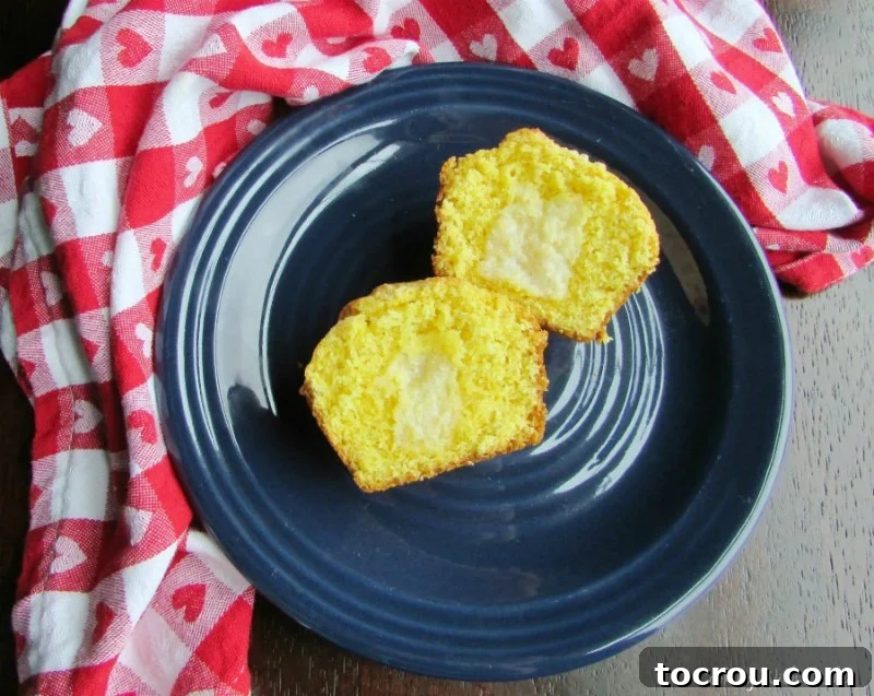 A golden brown corn muffin, expertly split in half and generously spread with melted butter, showcasing its inviting crumb texture.