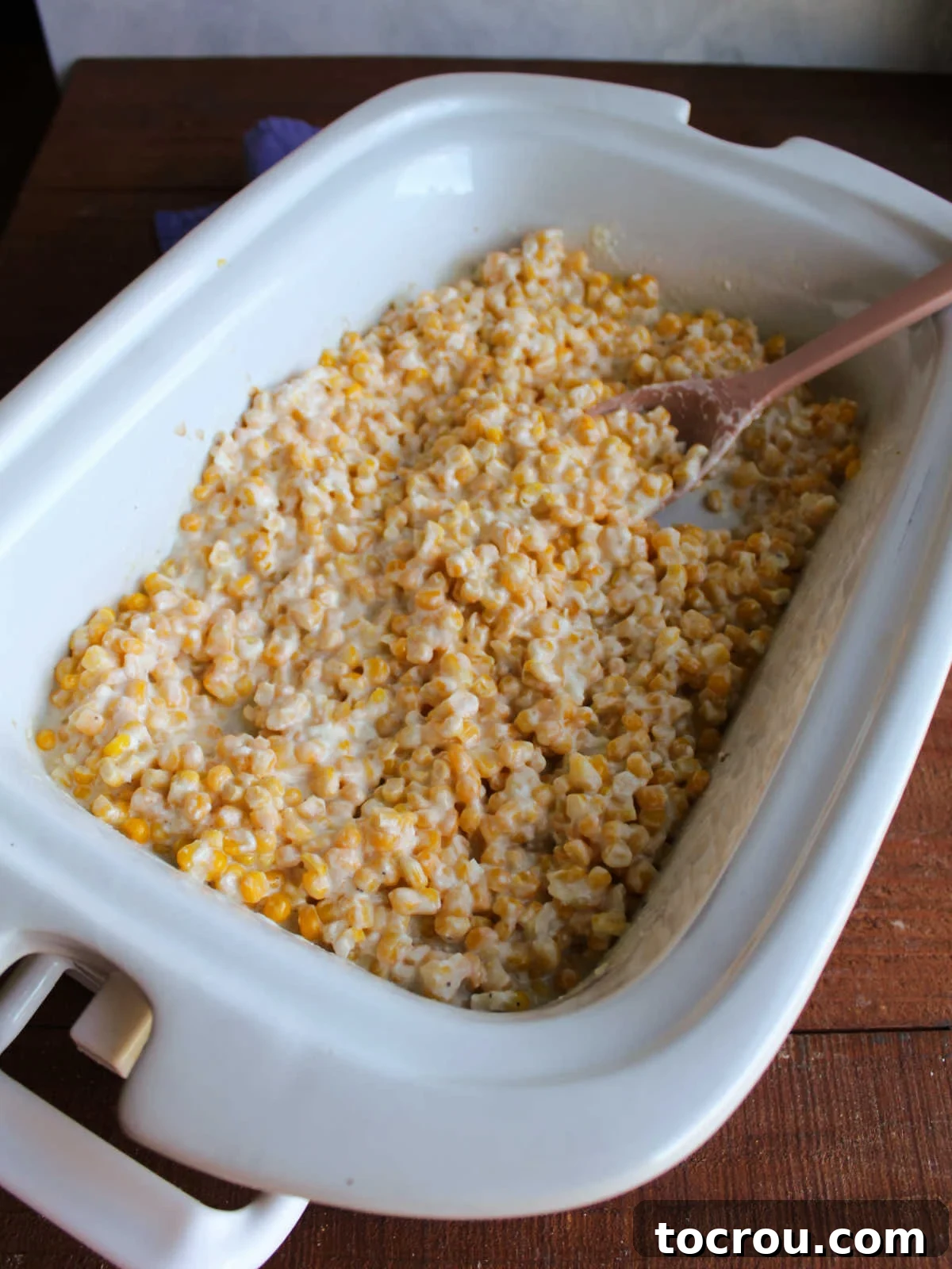 Cooked Crockpot Creamed Corn in a Slow Cooker A rectangular slow cooker brimming with perfectly cooked creamy corn, each kernel glistening with melted butter and cream cheese.