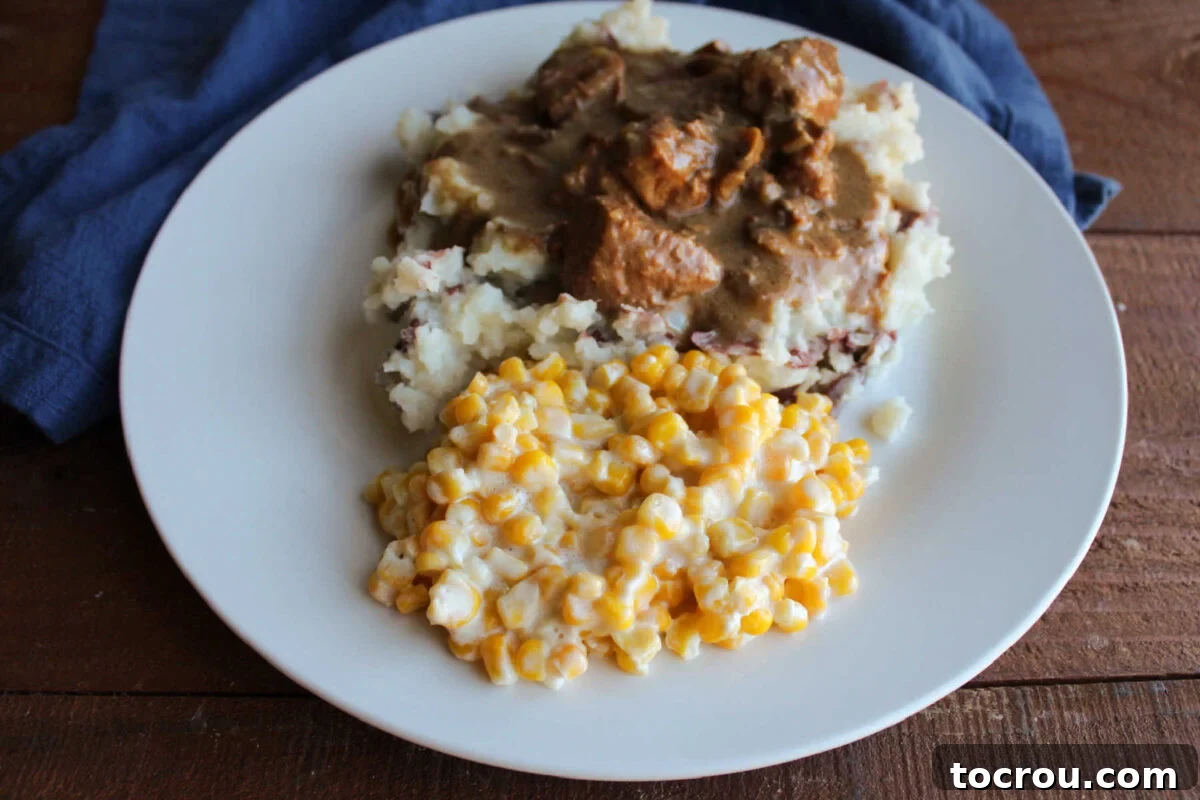 Creamed Corn with Roast Beef and Mashed Potatoes A dinner plate with a generous scoop of creamy corn alongside fluffy mashed potatoes, all complemented by tender roast beef in rich gravy.