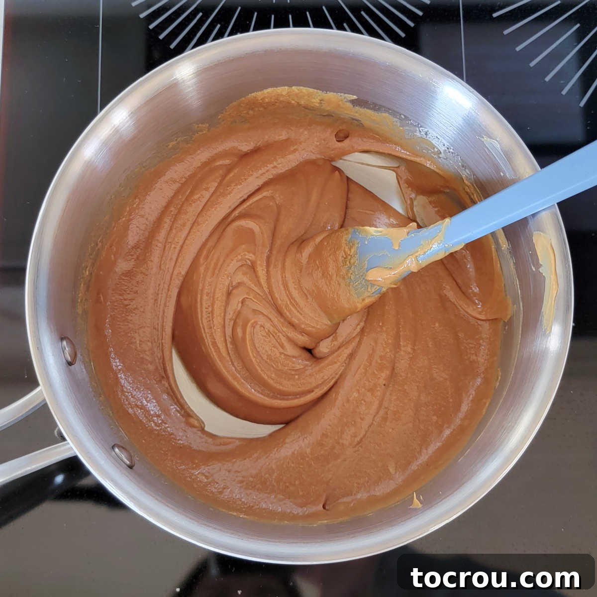 Saucepan with warm, glistening peanut butter and maple syrup mixture, ready for cereal.