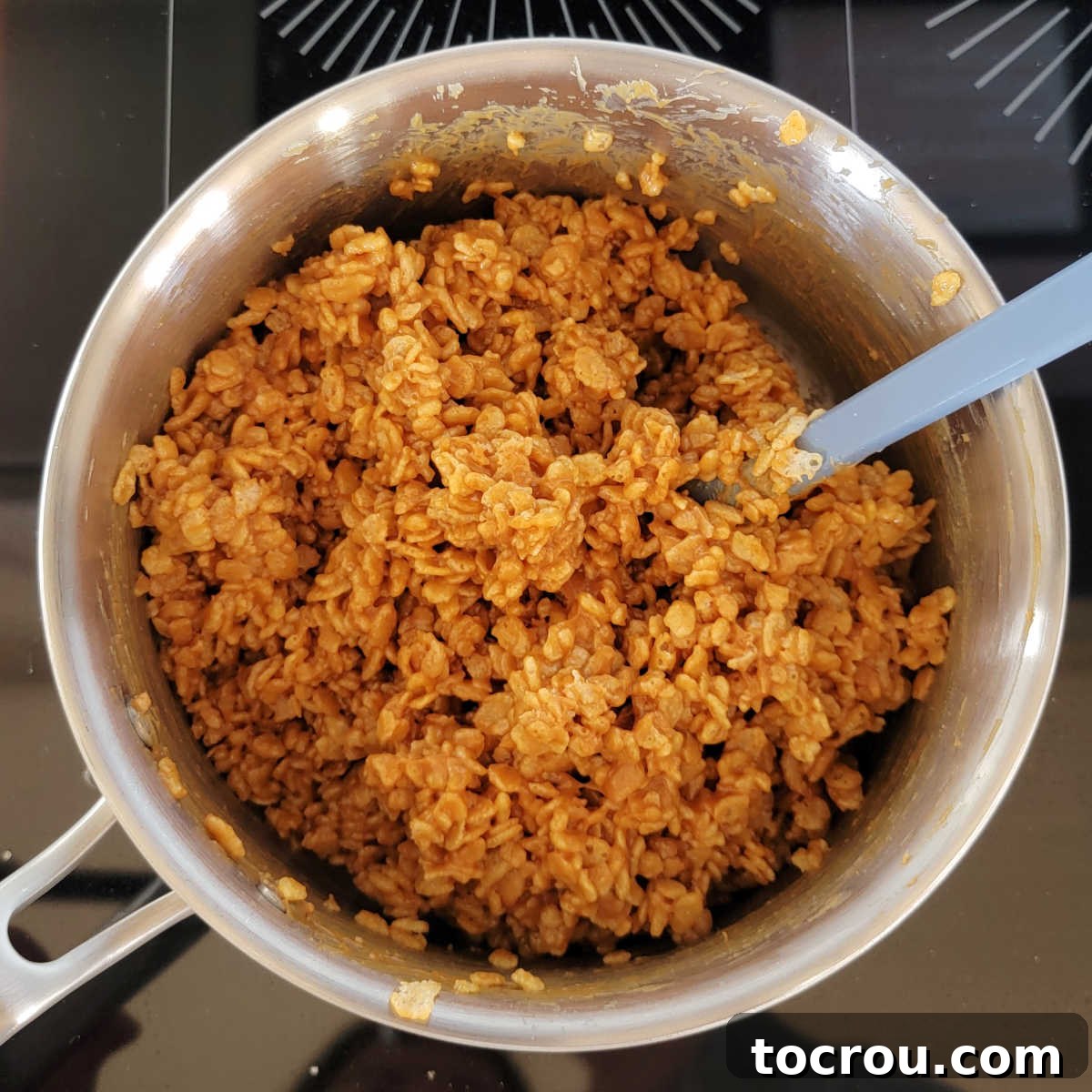 Saucepan with rice krispie cereal thoroughly coated in the peanut butter and maple syrup mixture, ready for pressing.