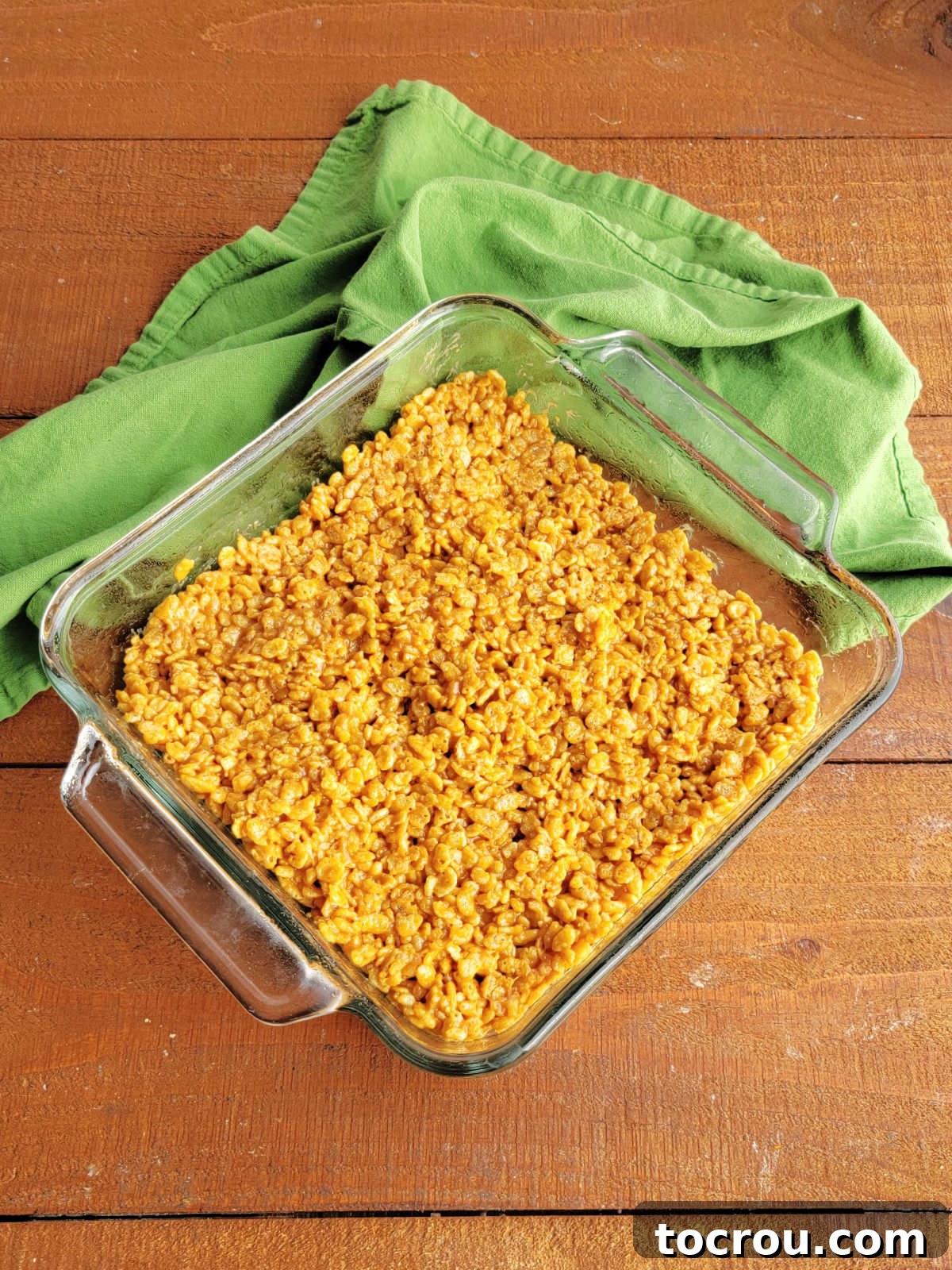 Square glass baking dish filled with unset maple peanut butter rice krispie treats, waiting for frosting.