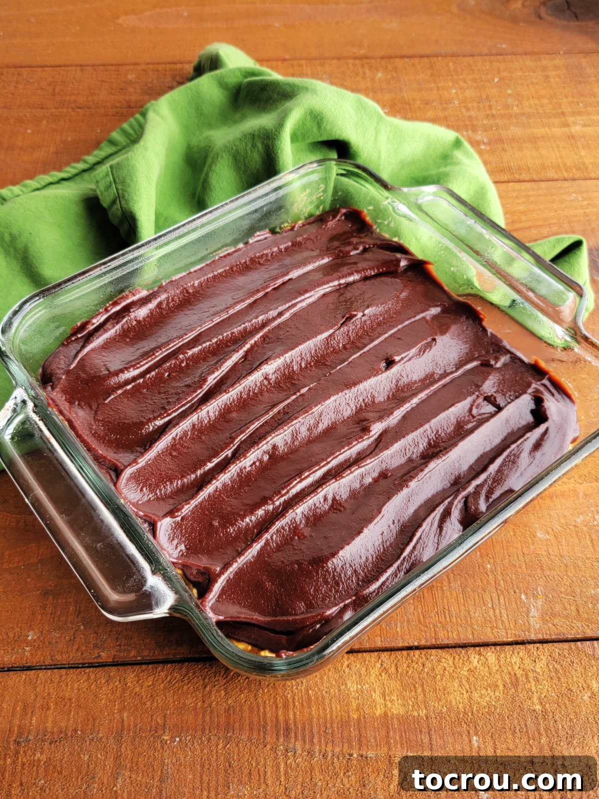 Square glass baking dish with maple peanut butter rice krispie treats generously topped with homemade fudge icing.