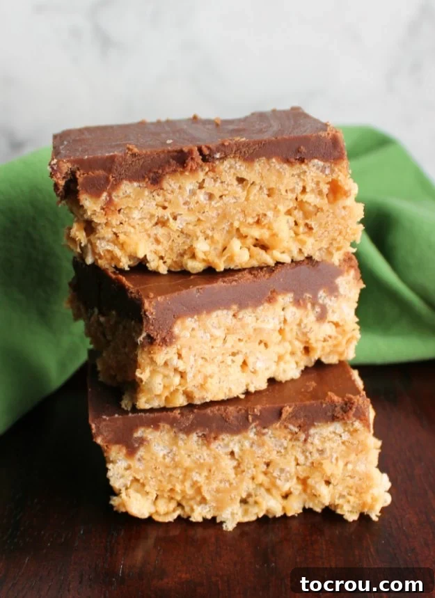 Stack of peanut butter maple rice krispie treats with fudge icing, showing off a perfectly chewy and crisp texture.