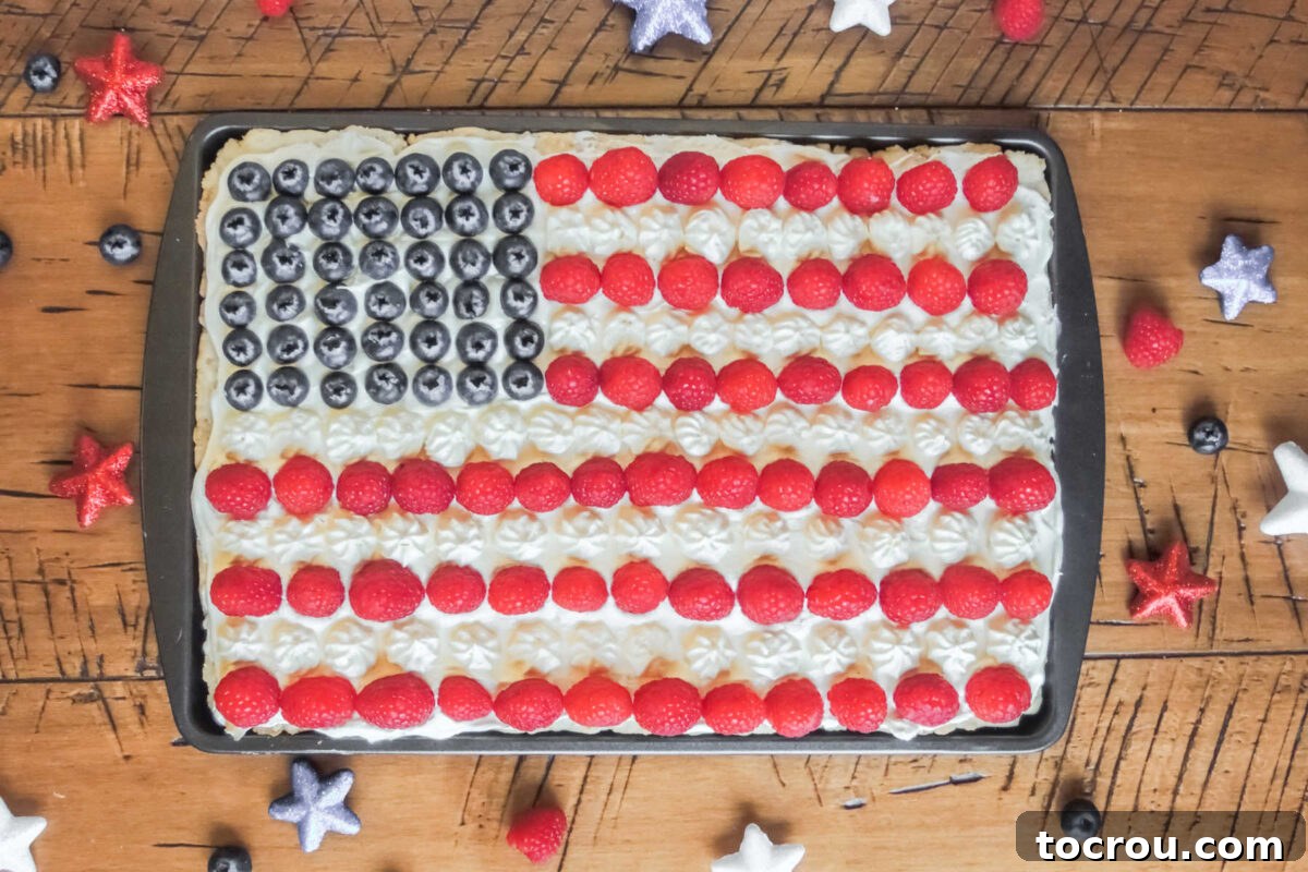 Stars and Stripes Cookie Squares 2 Tray filled with cookie bars topped with white frosting and raspberries for the red stripes and blueberries for the blue and white star portion of the american flag.