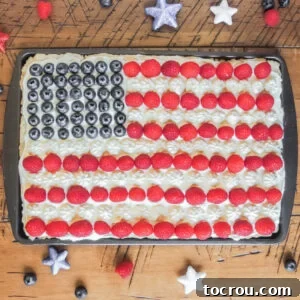 Stars and Stripes Cookie Squares 13 Cookie bar topped with frosting, raspberries and blueberries arranged to look like an American flag.