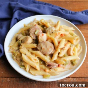 A inviting plate of pastalaya, featuring penne pasta bathed in a lightly cheesy sauce, mingled with savory sausage, tender chicken, colorful peppers, onions, and celery, perfectly ready to be enjoyed.