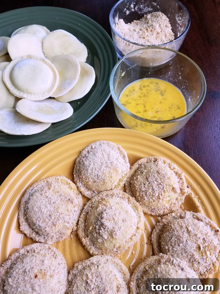 Plate of fresh ravioli coated in egg wash and seasoned breadcrumbs, ready for the air fryer.
