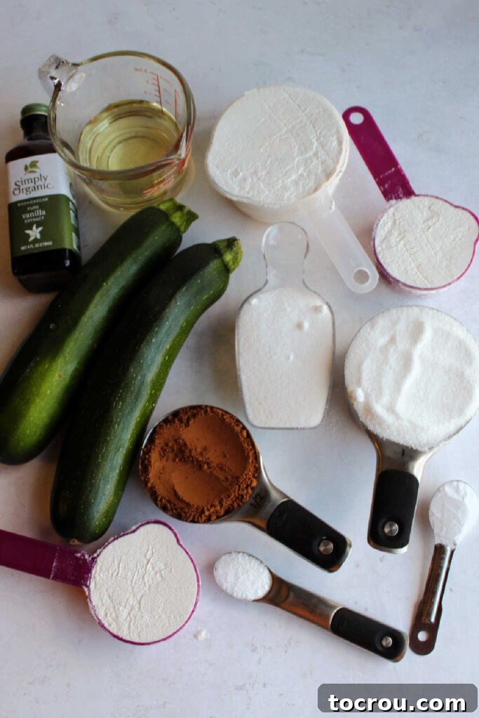 Ingredients ready to be made into chocolate zucchini cake, including shredded zucchini, dry ingredients, and wet ingredients.