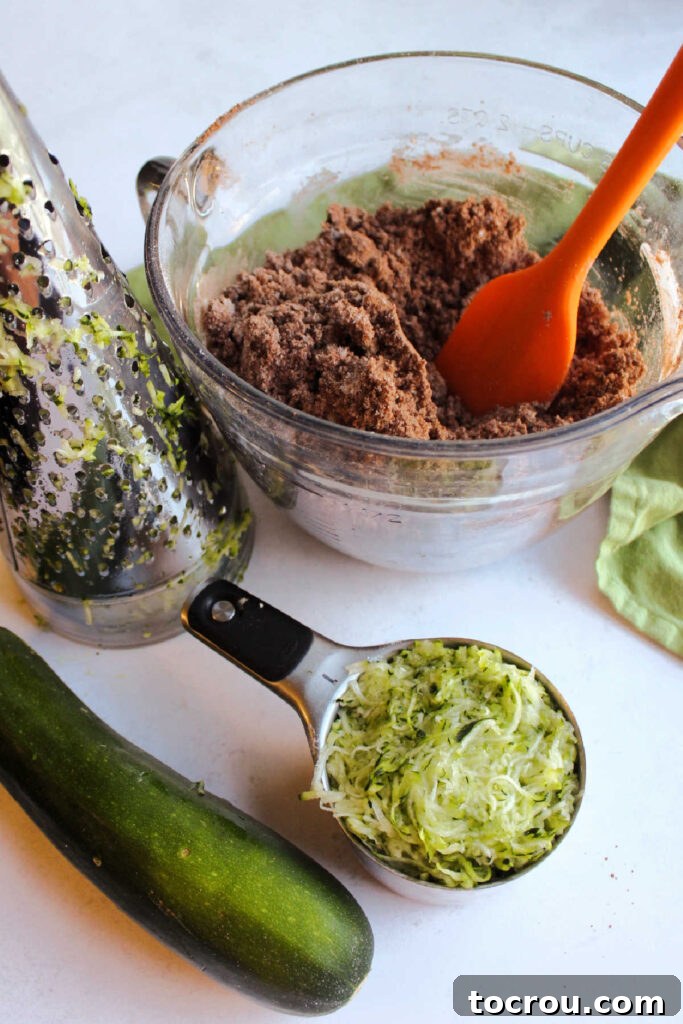 Shredding zucchini to add to the chocolate cake mix, ensuring fine texture and retaining moisture.