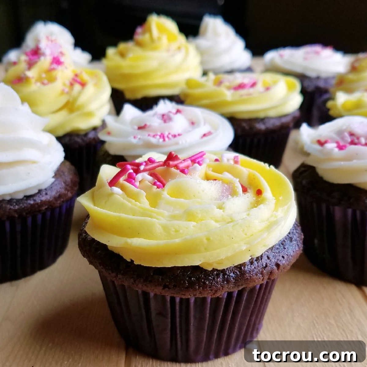 Banana makes these cupcakes moist and delicious. They are the perfect combo of chocolate, banana and cake! Rich chocolate cupcakes decorated with white and yellow condensed milk buttercream and pink and white sprinkles.