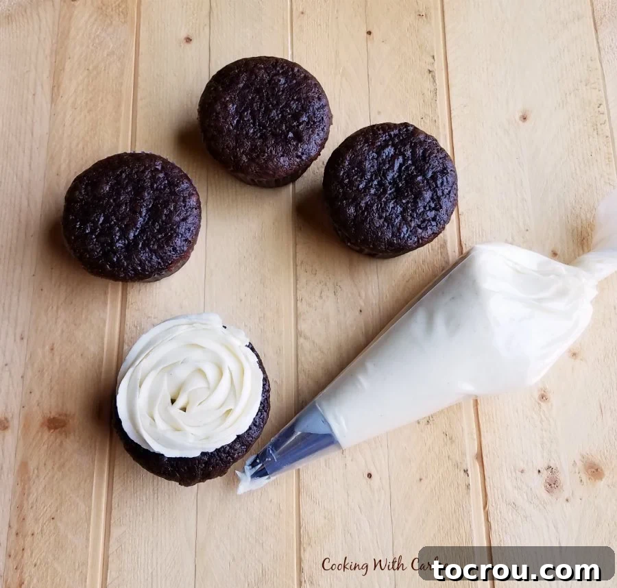 Decadent Chocolate Banana Cupcakes 2 chocolate banana cupcakes with white condensed milk buttercream being piped on one.