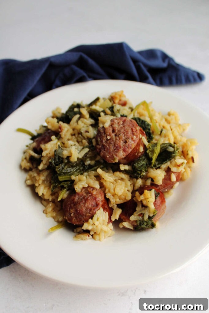 A close-up of a dinner plate showcasing a generous serving of kielbasa, rice, and mustard greens, perfectly arranged and ready for a satisfying meal. The dish looks wholesome and inviting.