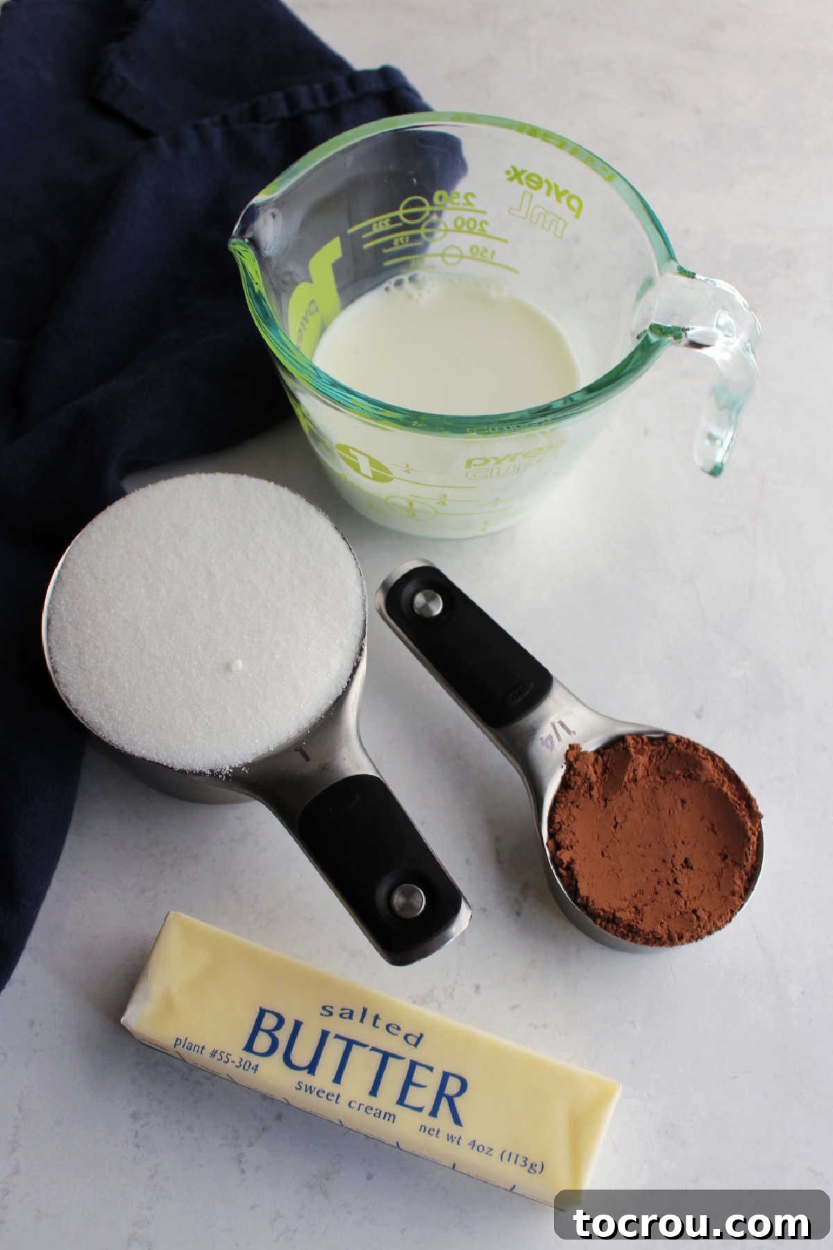 Ingredients: milk, cocoa powder, sugar and butter ready to be made into hot fudge sauce.