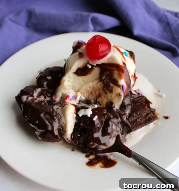 brownie topped with ice cream, hot fudge and a cherry