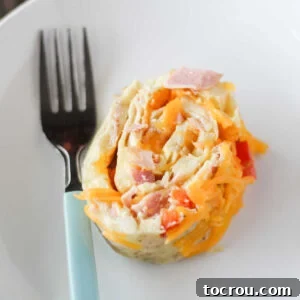 Slice of denver omelet roll with ham, pepper and eggs rolled around a melted cheese center.