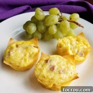 3 mini ham and cheese quiche in wonton wrappers on plate with bunch of grapes.