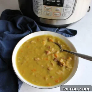 Bowl of thick split pea soup with carrots and ham in front of instant pot it was cooked in.