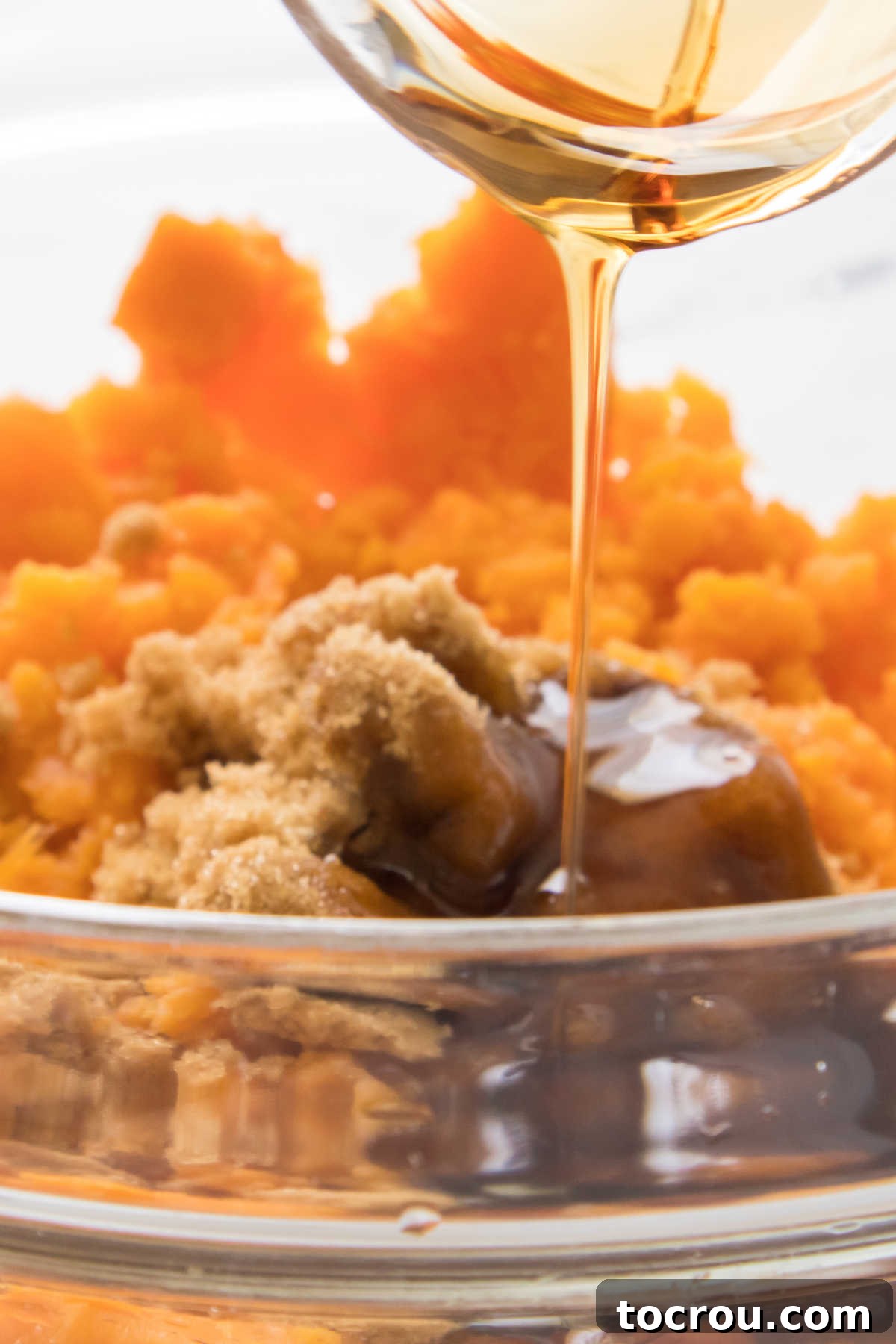 Pouring maple syrup into mashed sweet potatoes.