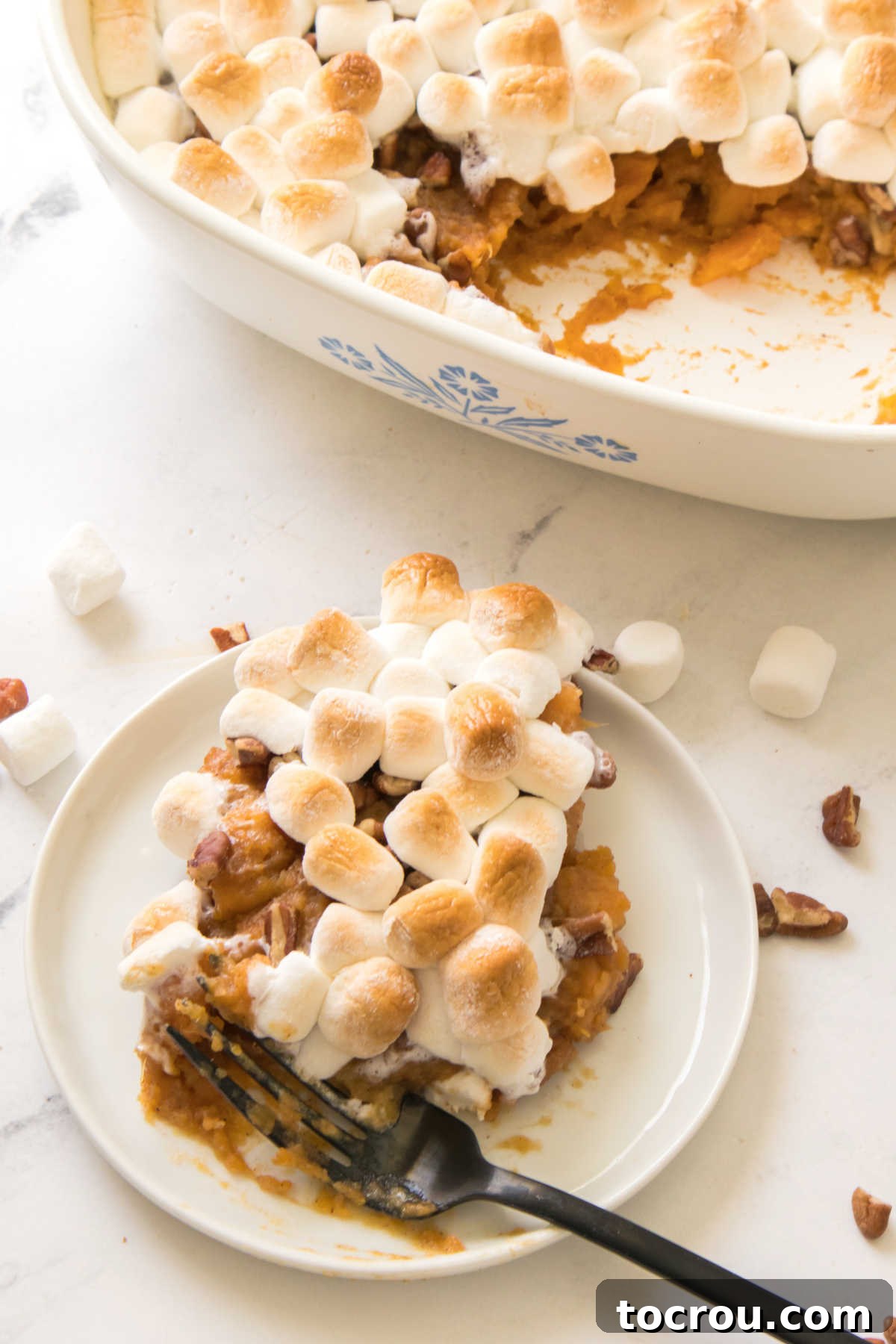 Serving of sweet potatoes topped with pecans and gooey marshmallows. 
