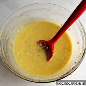 A smooth, creamy mixture of cream cheese, powdered sugar, and eggs is being beaten in a mixing bowl, ready to become the gooey filling.
