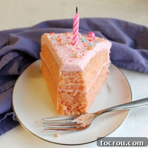 Big slice of pink velvet cake on plate with a bite taken out of the end and a blow out candle on top.