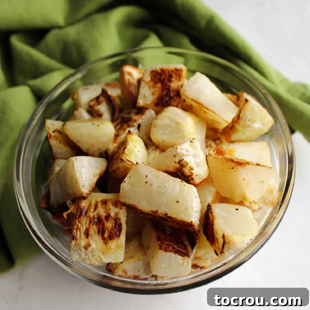 Bowl of roasted chunks of kohlrabi with garlic and Parmesan cheese, ready to be served as a delicious side dish.