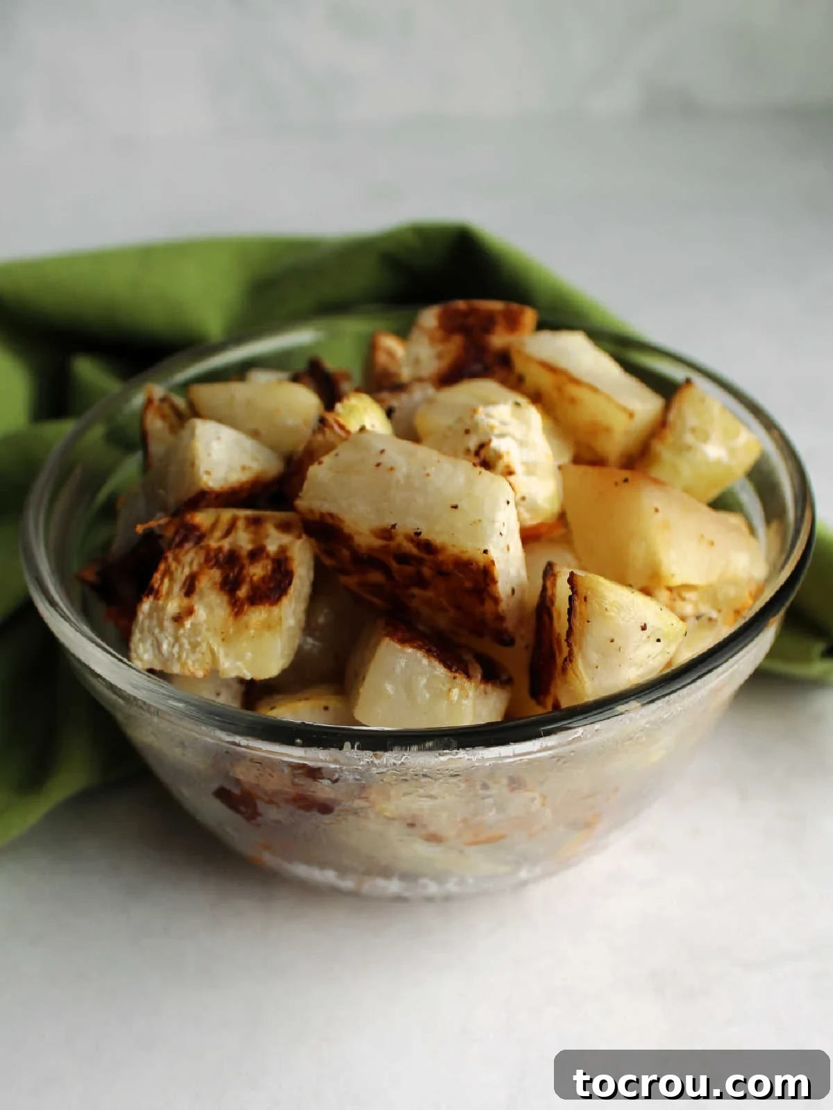 Small glass bowl filled with perfectly roasted kohlrabi chunks, seasoned and ready to be savored as a delightful side dish.