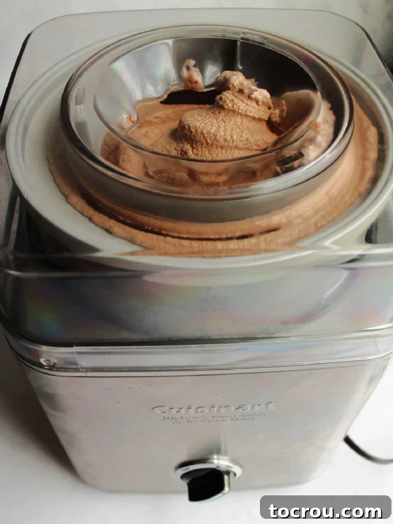 Churning chocolate ice cream in an ice cream maker, showcasing the creamy consistency before final freezing.