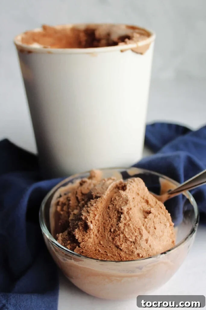 A bowl of homemade chocolate ice cream presented in front of a larger storage container, ready to be enjoyed.