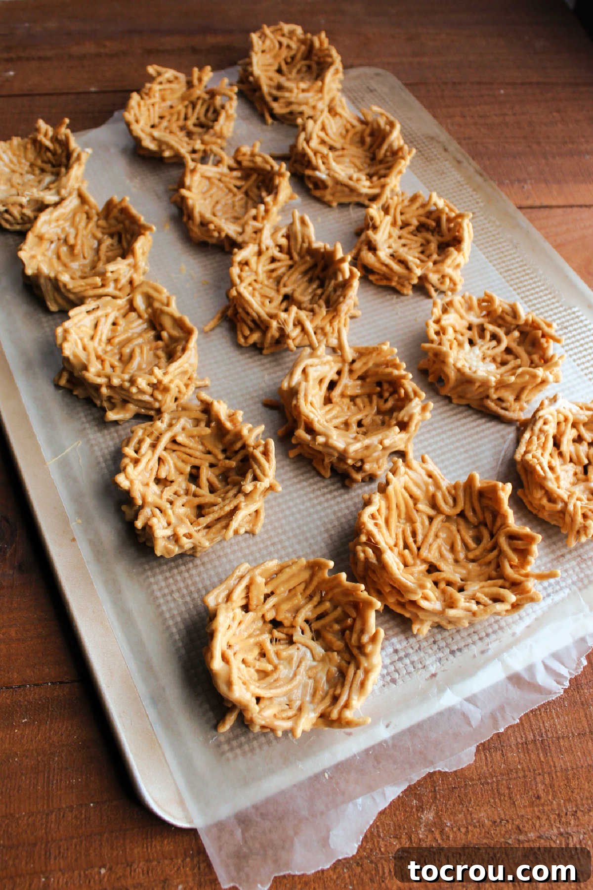 No-Bake Nests Setting on Wax Paper Freshly made marshmallow and peanut butter chow mein nests setting up on wax paper, their intricate shapes ready to hold festive candy fillings.