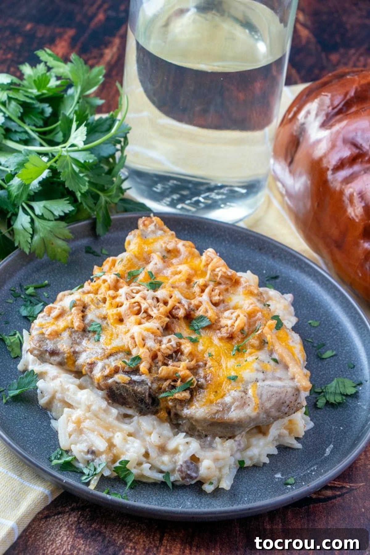 dinner plate of pork chop and potato casserole, parsley and glass of water